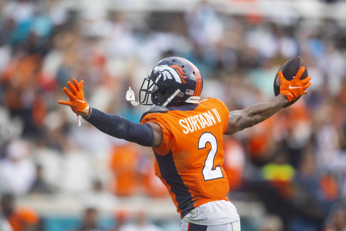 Pat Surtain II puts his hands out to the side holding the football in one hand